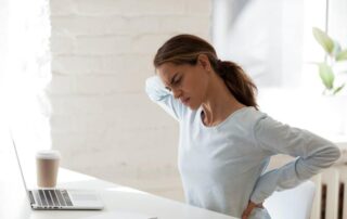 Woman stretching with back pain at desk